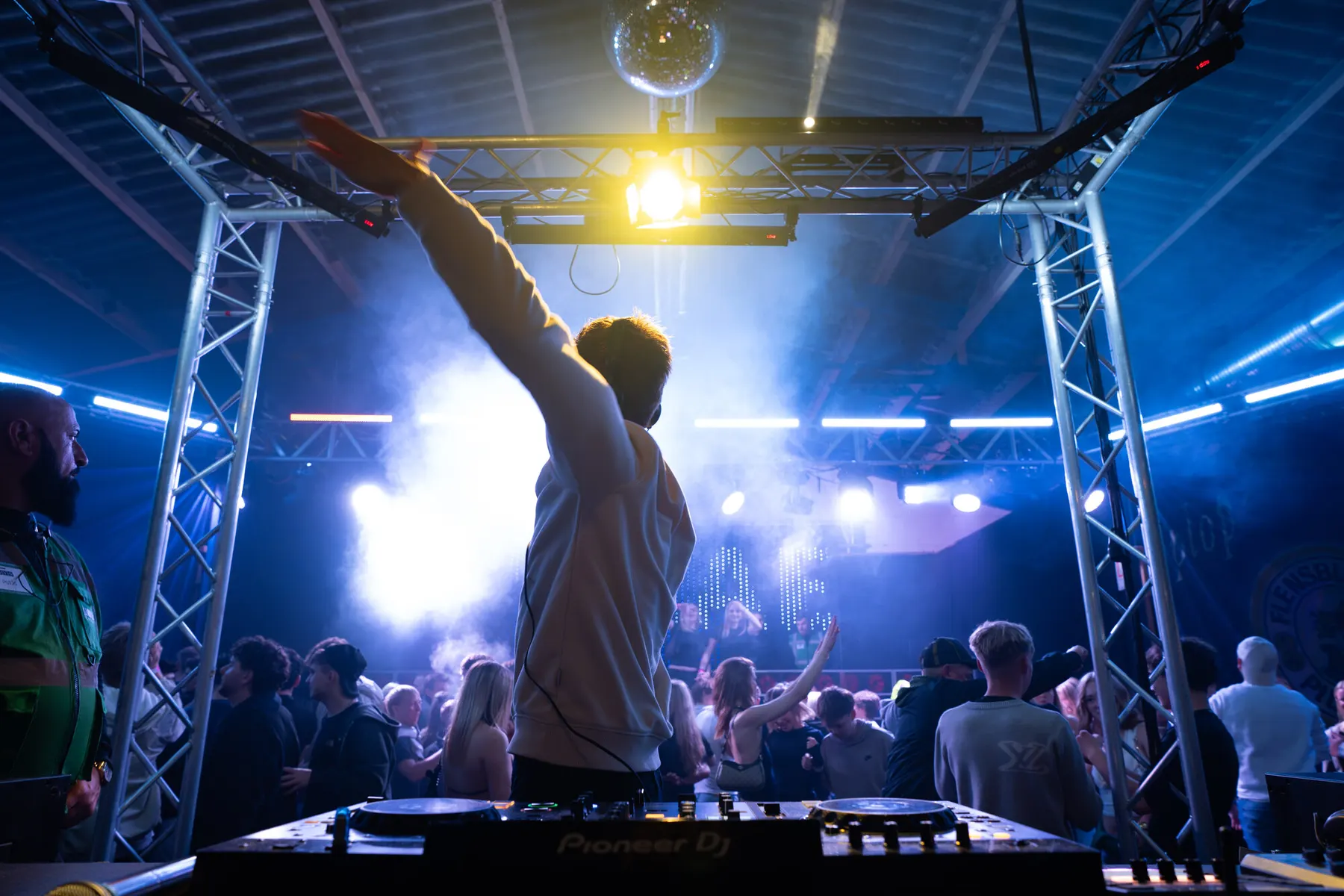 DJ von hinten, Arme oben, vor der vollen Wiesenhalle